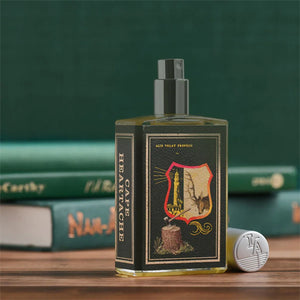 Imaginary Authors - Cape Heartache Parfumspray mit detailreichem Etikett und offenem Zerstäuber vor grünem Hintergrund
