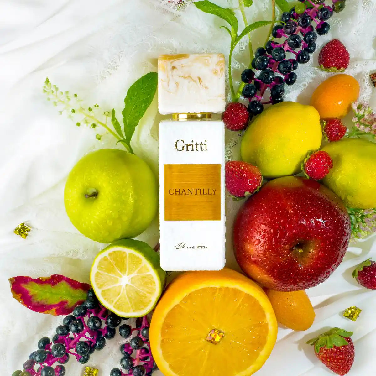 Gritti - White Collection - Chantilly Parfumflakon umgeben von frischen Zitrusfrüchten und roten Beeren auf hellem Stoff