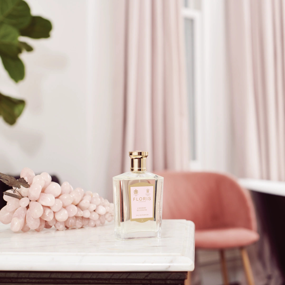 Floris - Cherry Blossom eleganter Flakon mit goldenem Verschluss auf Marmorplatte vor samtrosa Sessel und Vorhängen