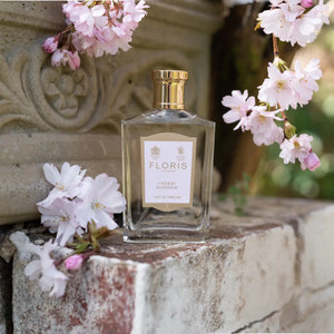 Floris - Cherry Blossom klarer Parfümflakon mit goldfarbenem Verschluss umgeben von zarten Kirschblüten in natürlicher Umgebung