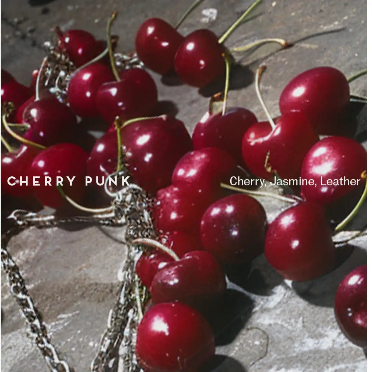 Room 1015 - Cherry Punk mit glänzenden Kirschen und silberner Kette auf rauem Untergrund inszeniert