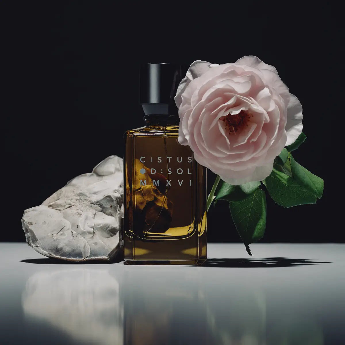 D:SOL MMXVI - Cistus Parfumflakon in bernsteinfarbenem Glas mit zarter Blüte und natürlichem Stein im Arrangement