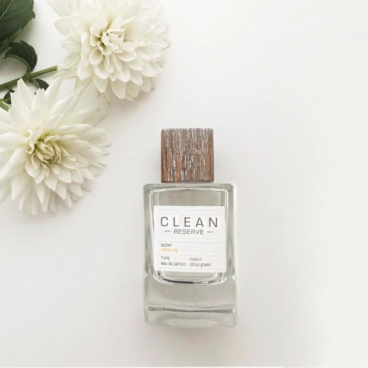 Clean Perfume - Reserve - Citron Fig [reserve blend] Parfum mit Holzdeckel und weißen Blumen auf hellem Untergrund