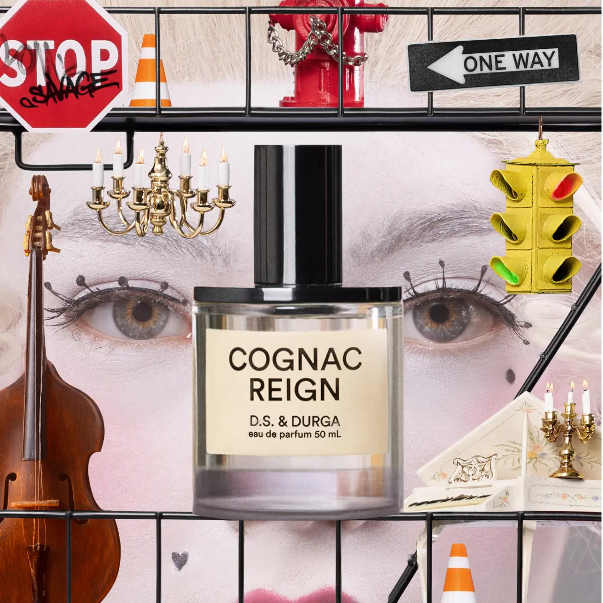 D.S. & Durga - Cognac Reign Parfumflakon vor künstlerischer Collage mit Geige, Kerzenleuchtern und Ampelspielzeug