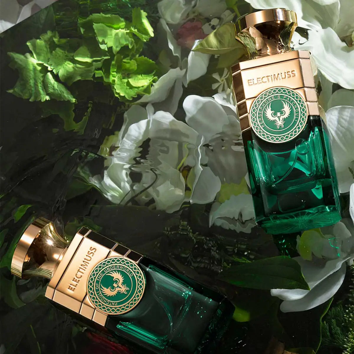 Electimuss - Persephone's Patchouli Flakon mit grünem Glas und goldfarbenem Verschluss in luxuriöser Optik vor floralem Hintergrund