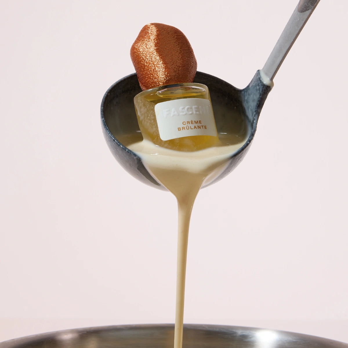 Fascent - Crème Brûlante Parfumflakon präsentiert in Kelle mit cremigem, vanillig-holzigem Aroma vor hellem Hintergrund