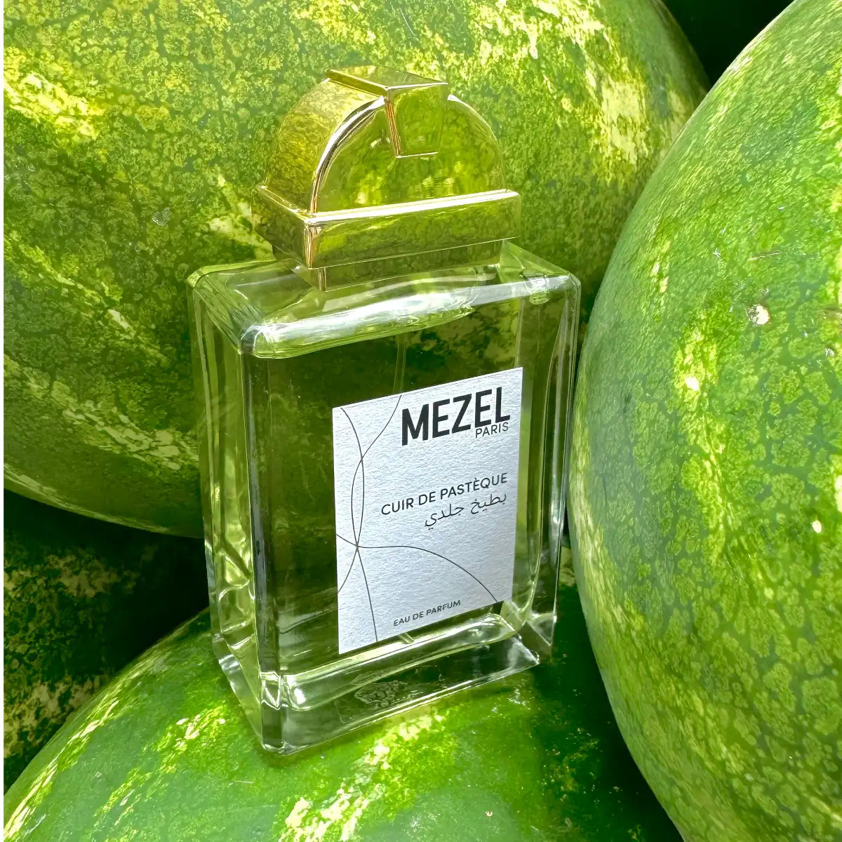 Mezel Paris - Cuir de Pastèque Parfumflakon mit goldfarbenem Verschluss umgeben von frischen Wassermelonen
