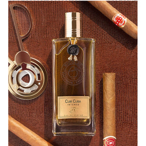 Nicolaï - Cuir Cuba Intense Parfümflakon mit goldfarbenem Verschluss auf Lederhintergrund mit Zigarren und Humidorzubehör
