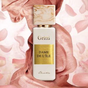 Gritti - White Collection - Dame de L'Île Parfumflakon mit goldenem Label und marmoriertem Verschluss vor zart rosa Samt und Blütenblättern