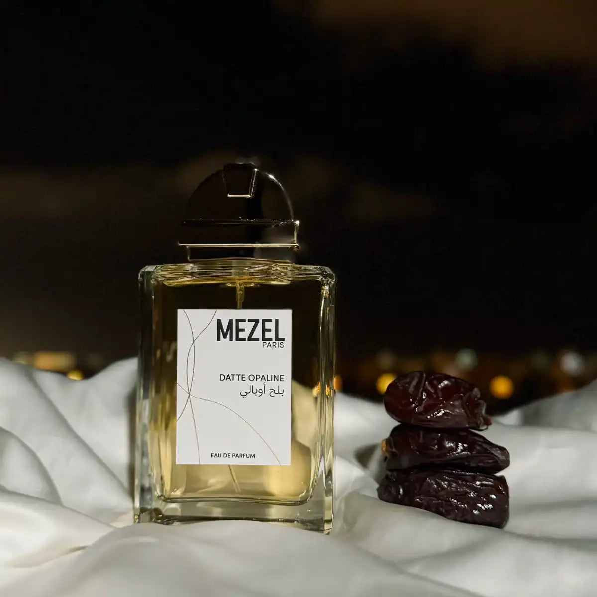 Mezel Paris - Datte Opaline Parfumflakon mit goldfarbenem Verschluss neben drei Datteln vor dunklem Hintergrund