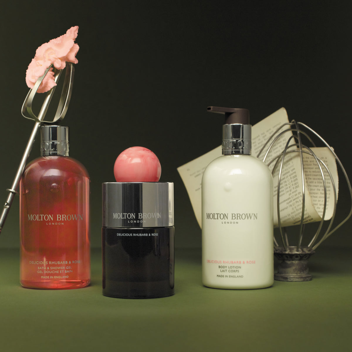 Molton Brown - Delicious Rhubarb & Rose Set mit Duschgel, Bodylotion und Parfumflakon vor dunklem Hintergrund
