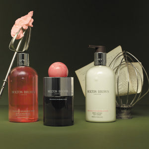 Molton Brown - Delicious Rhubarb & Rose Set mit Duschgel, Bodylotion und Parfumflakon vor dunklem Hintergrund