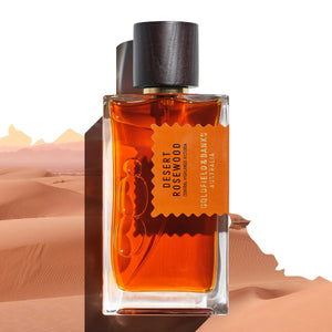 Goldfield & Banks - Native Collection - Desert Rosewood Parfumflakon mit bernsteinfarbener Flüssigkeit und dunklem Holzverschluss vor Wüstenkulisse