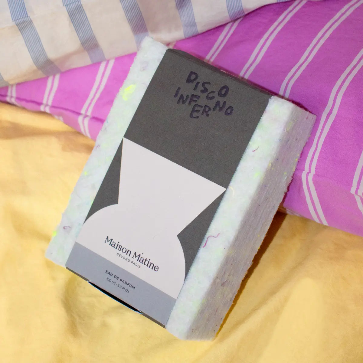 Maison Matine - Night Fever Collection - Disco Inferno zeigt Verpackung mit modernem Design auf farbigem Stoffhintergrund