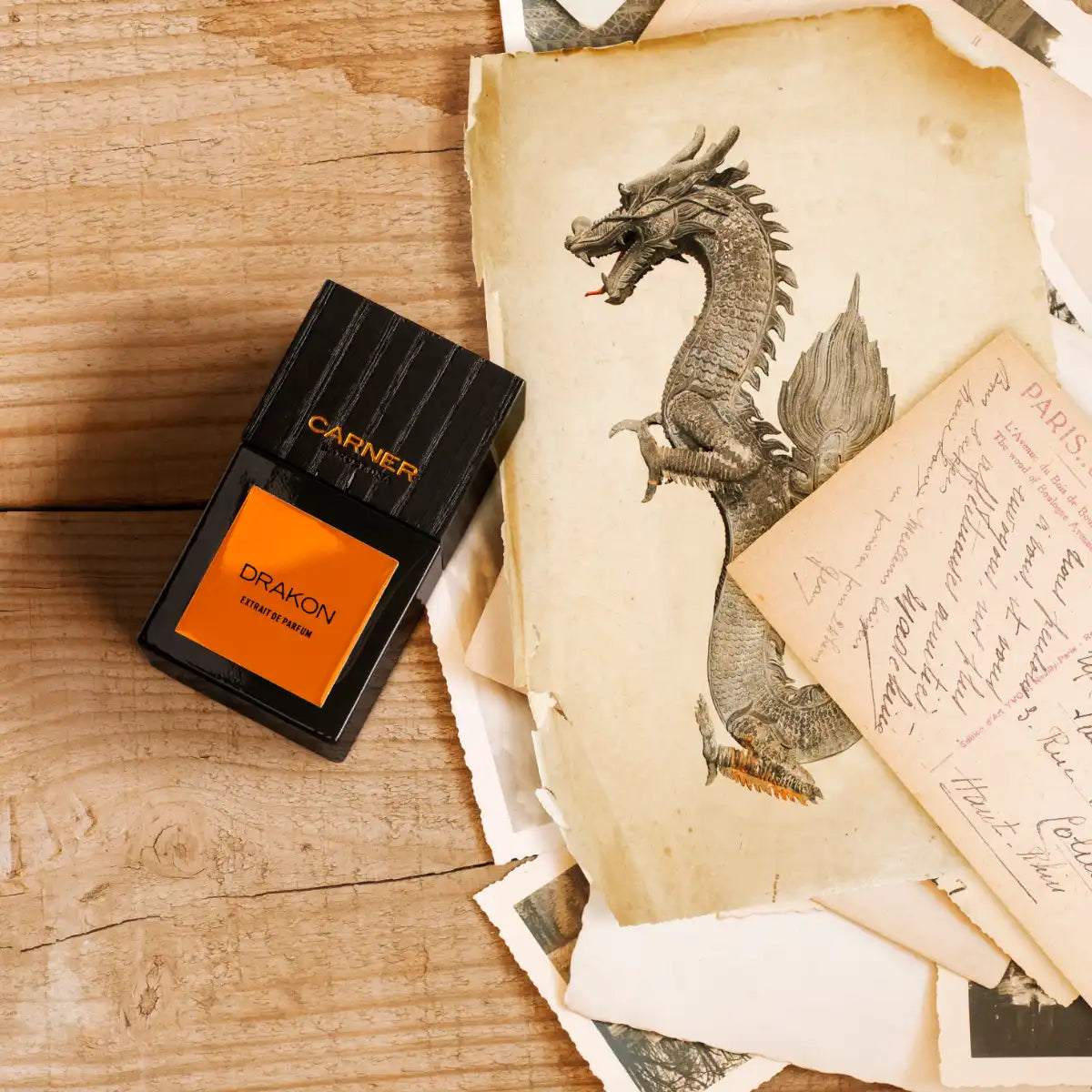 Carner Barcelona - Bestial Collection - Drakon Parfumflakon mit schwarzem Glas und orangefarbenem Etikett auf Holztisch