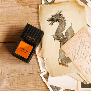 Carner Barcelona - Bestial Collection - Drakon Parfumflakon mit schwarzem Glas und orangefarbenem Etikett auf Holztisch