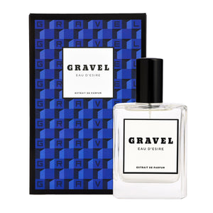 Gravel - Eau D'Esire Parfumflakon mit schwarzem Verschluss vor blau-geometrischer Verpackung auf weißem Hintergrund