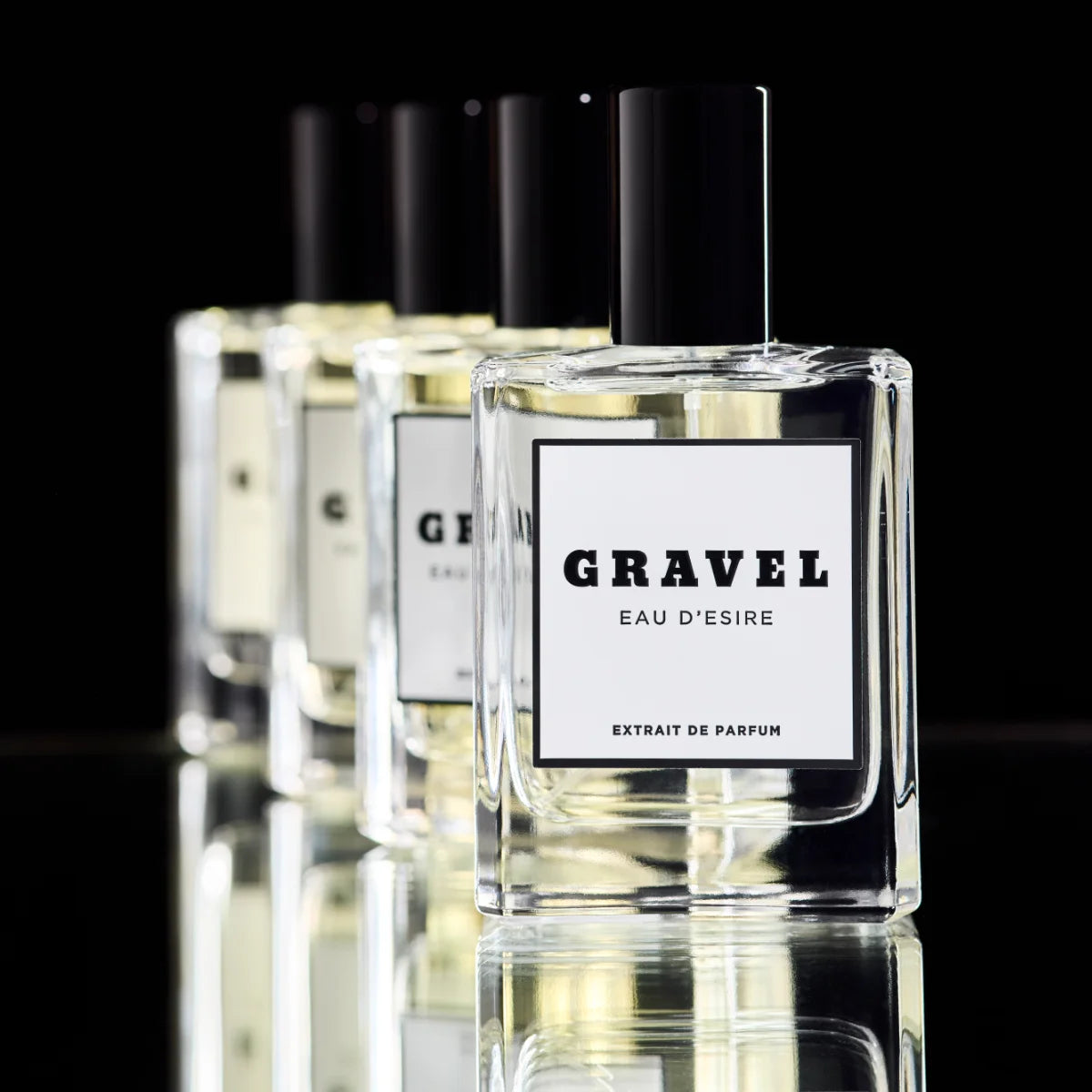 Gravel - Eau D'Esire Parfumflakon mit schwarzem Deckel in klarer Glasflasche vor schwarzem Hintergrund und Spiegelung