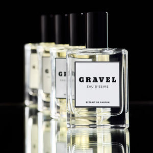 Gravel - Eau D'Esire Parfumflakon mit schwarzem Deckel in klarer Glasflasche vor schwarzem Hintergrund und Spiegelung