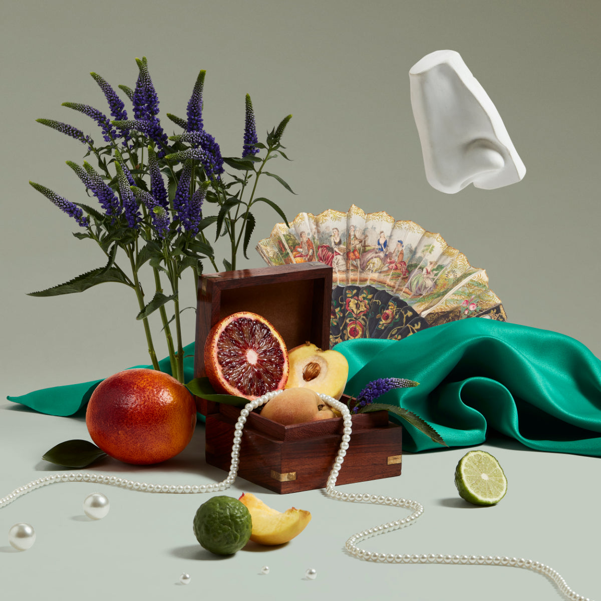 Penhaligon's - Trade Routes - Empressa mit Perlenkette, exotischen Früchten, grünem Stoff und kunstvollem Fächer vor neutralem Hintergrund
