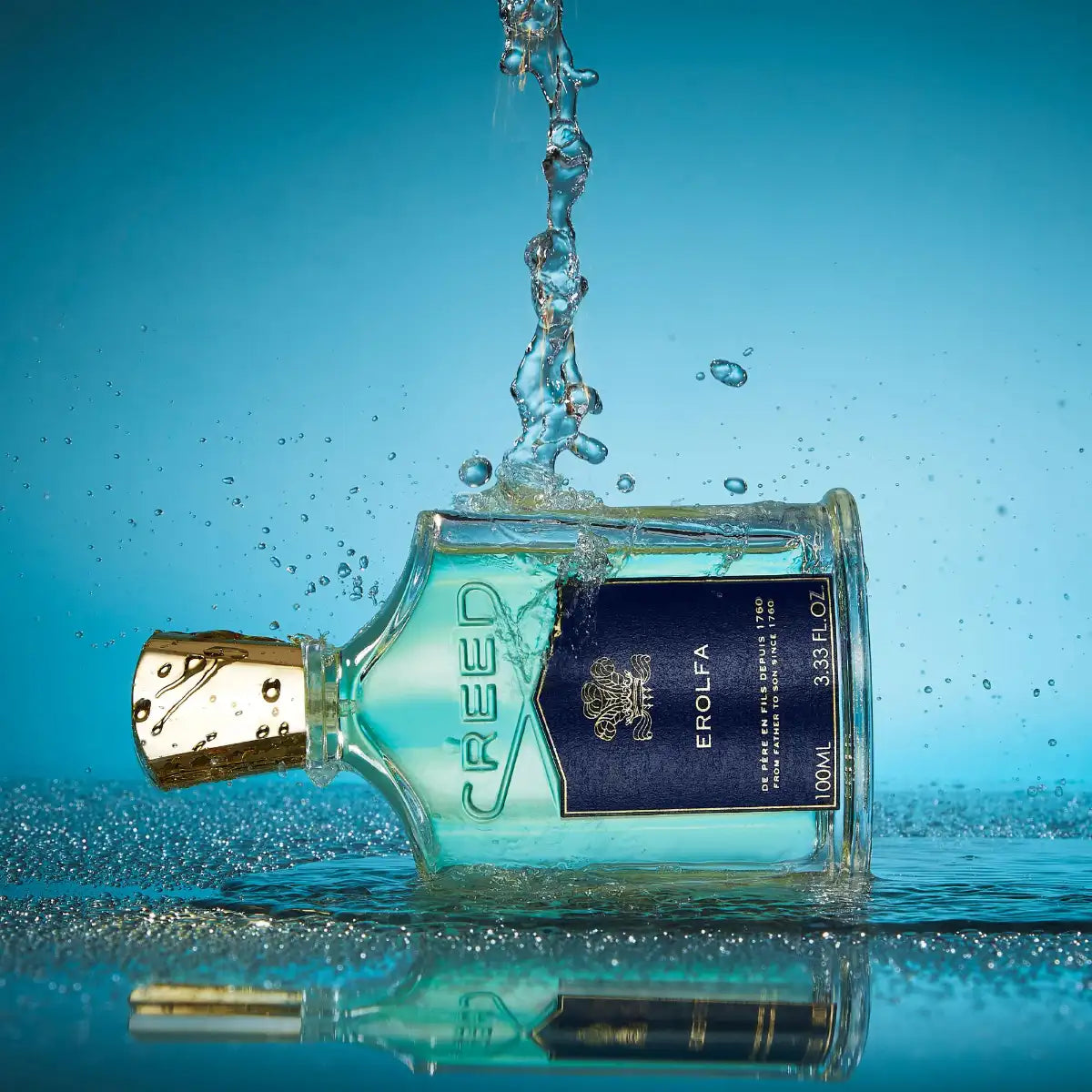Creed - Erolfa Parfumflakon mit blauem Etikett und goldenem Verschluss vor spritzendem Wasser auf blauem Hintergrund