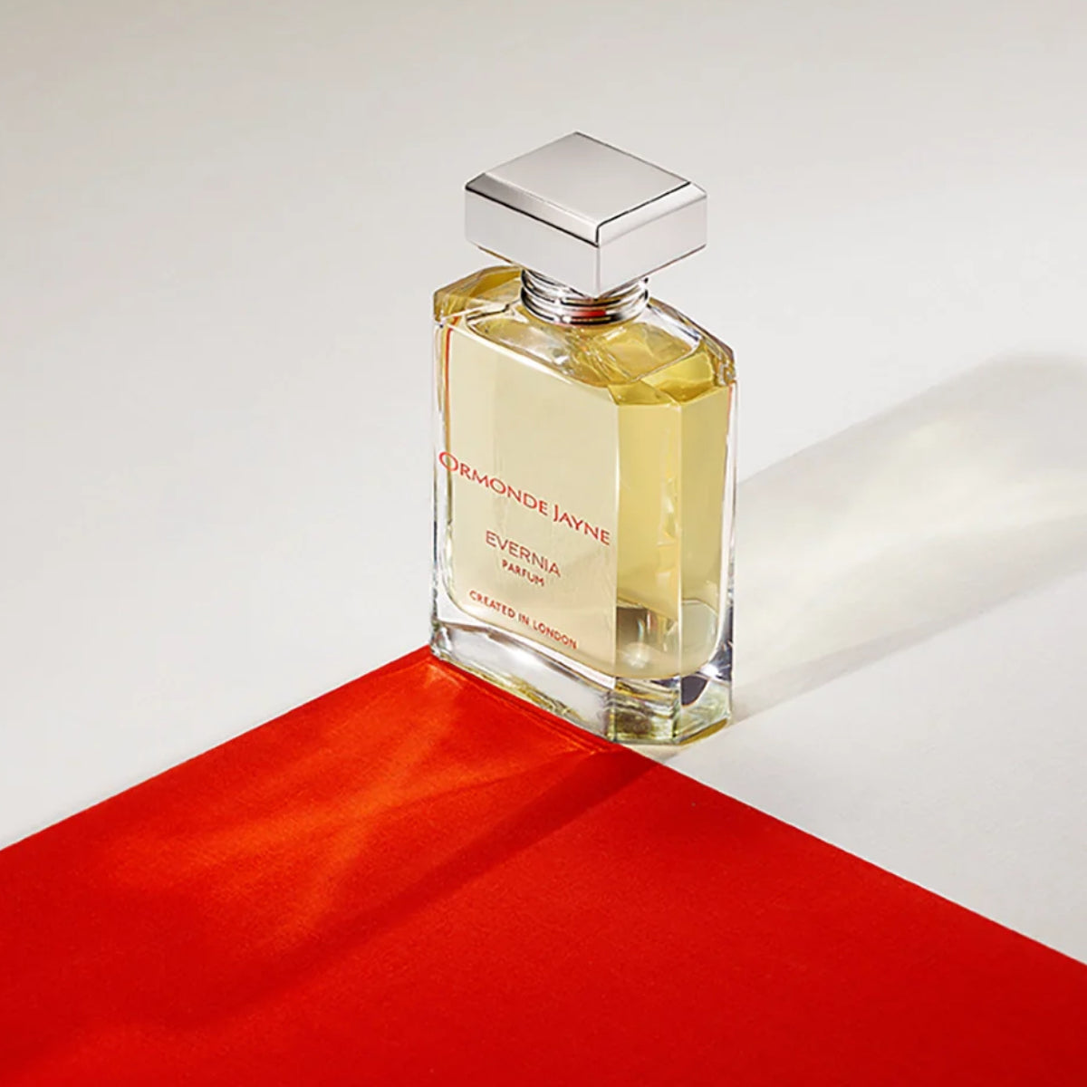 Ormonde Jayne - Evernia Parfumflakon mit klarer, eleganter Form und modernem, silberfarbenem Verschluss auf rotem Untergrund