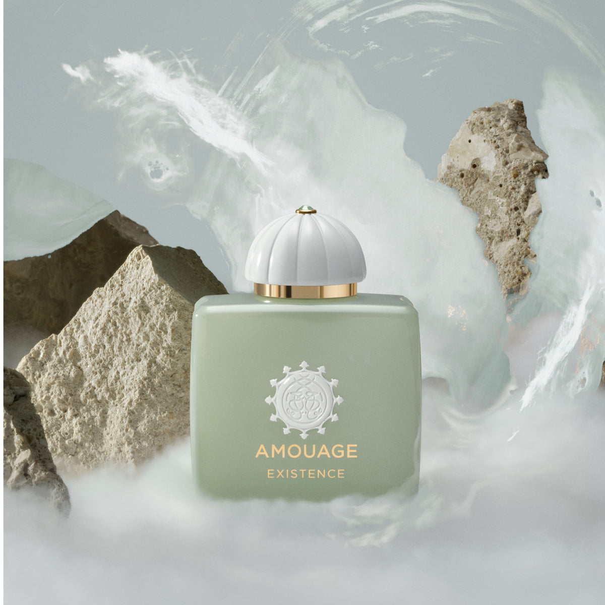 Amouage - Existence Parfumflakon in sanftem Grün mit goldenen Details vor nebliger, abstrakter Kulisse
