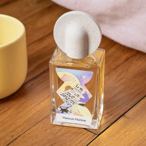 Maison Matine - Night Fever Collection - Un Jour sans Fin mit pastellfarbenem, künstlerischem Etikett und rundem beigem Verschluss auf Holzoberfläche