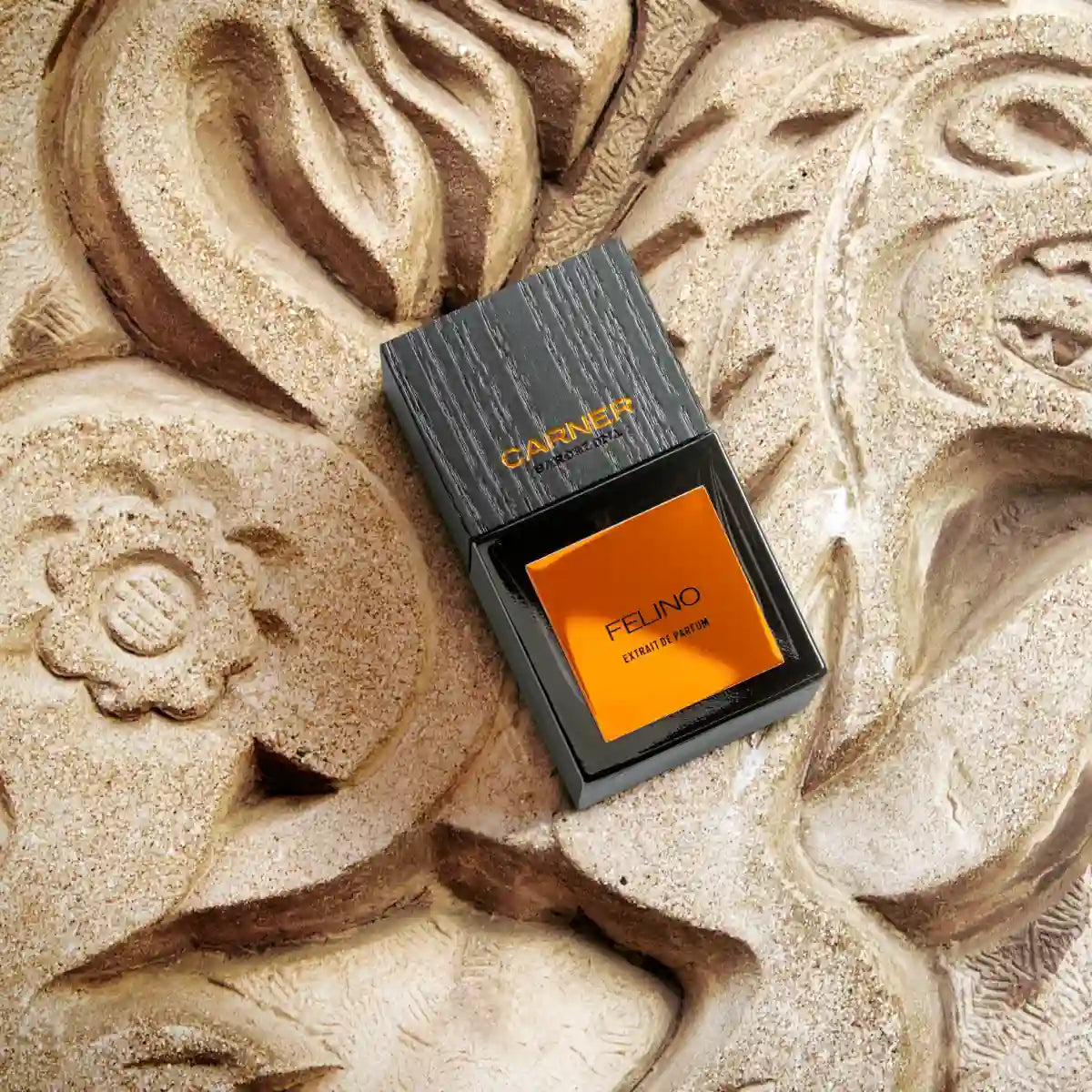 Carner Barcelona - Bestial Collection - Felino Parfumflakon mit schwarzem Deckel und auffälligem orangefarbenem Etikett auf Steinskulptur