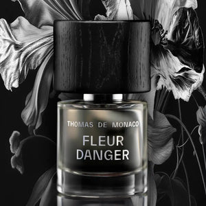Thomas de Monaco - Fleur Danger zeigt klaren Flakon mit schwarzem Holzdeckel vor dramatischer floral inspirierter Kulisse