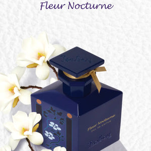 Isabey - Fleur Nocturne dunkelblauer Kristallflakon mit goldfarbenem Band und floralem Motiv vor hellem Hintergrund