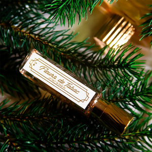 Cherigan - Fleurs de Tabac eleganter Flakon mit goldfarbenem Verschluss umgeben von Tannenzweigen in warmem Licht