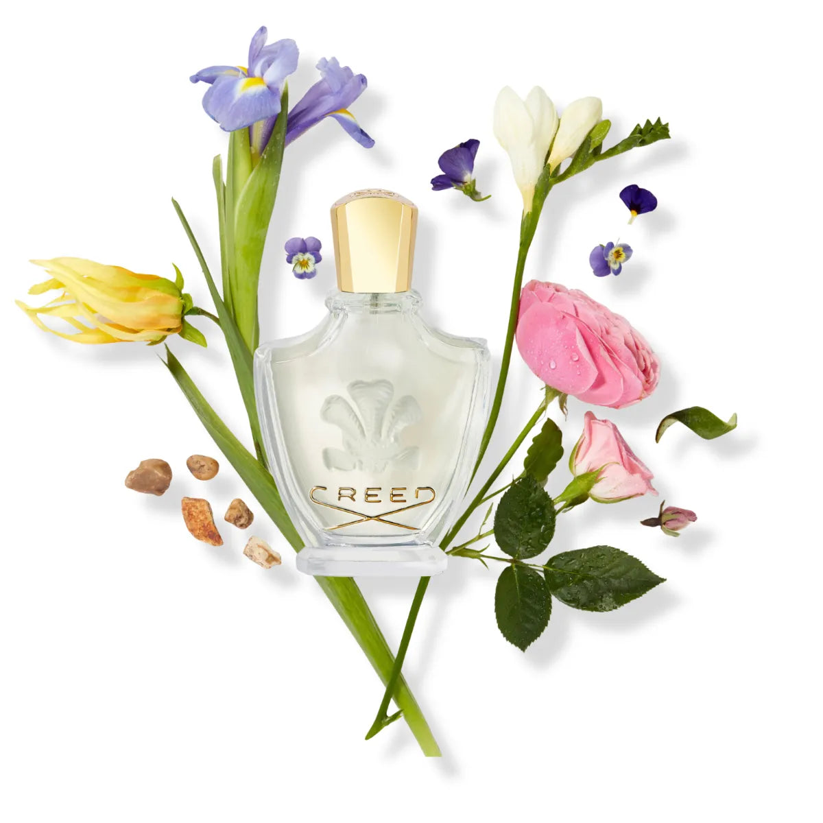 Creed - Fleurissimo Parfumflakon mit goldfarbenem Verschluss umgeben von zarten Blumen auf weißem Hintergrund