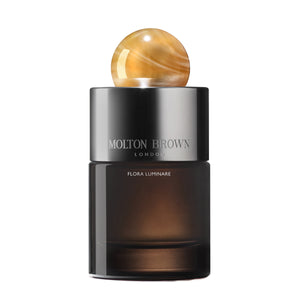 Molton Brown - Flora Luminare Parfumflakon mit dunklem Glas und bernsteinfarbenem kugelförmigem Verschluss vor weißem Hintergrund
