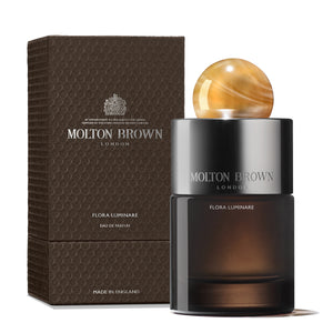 Molton Brown - Flora Luminare Parfumflakon mit mattschwarzem Glas und bernsteinfarbenem, kugelförmigem Verschluss vor weißem Hintergrund