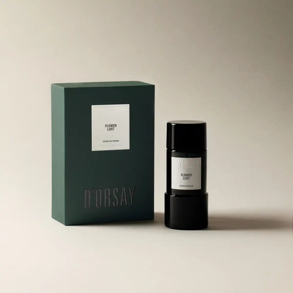 D'Orsay - Flower Lust Parfumflakon in schwarzem Design neben grünem Verpackungskarton vor beigem Hintergrund