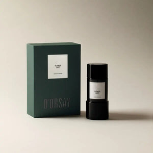 D'Orsay - Flower Lust Parfumflakon in schwarzem Design neben grünem Verpackungskarton vor beigem Hintergrund