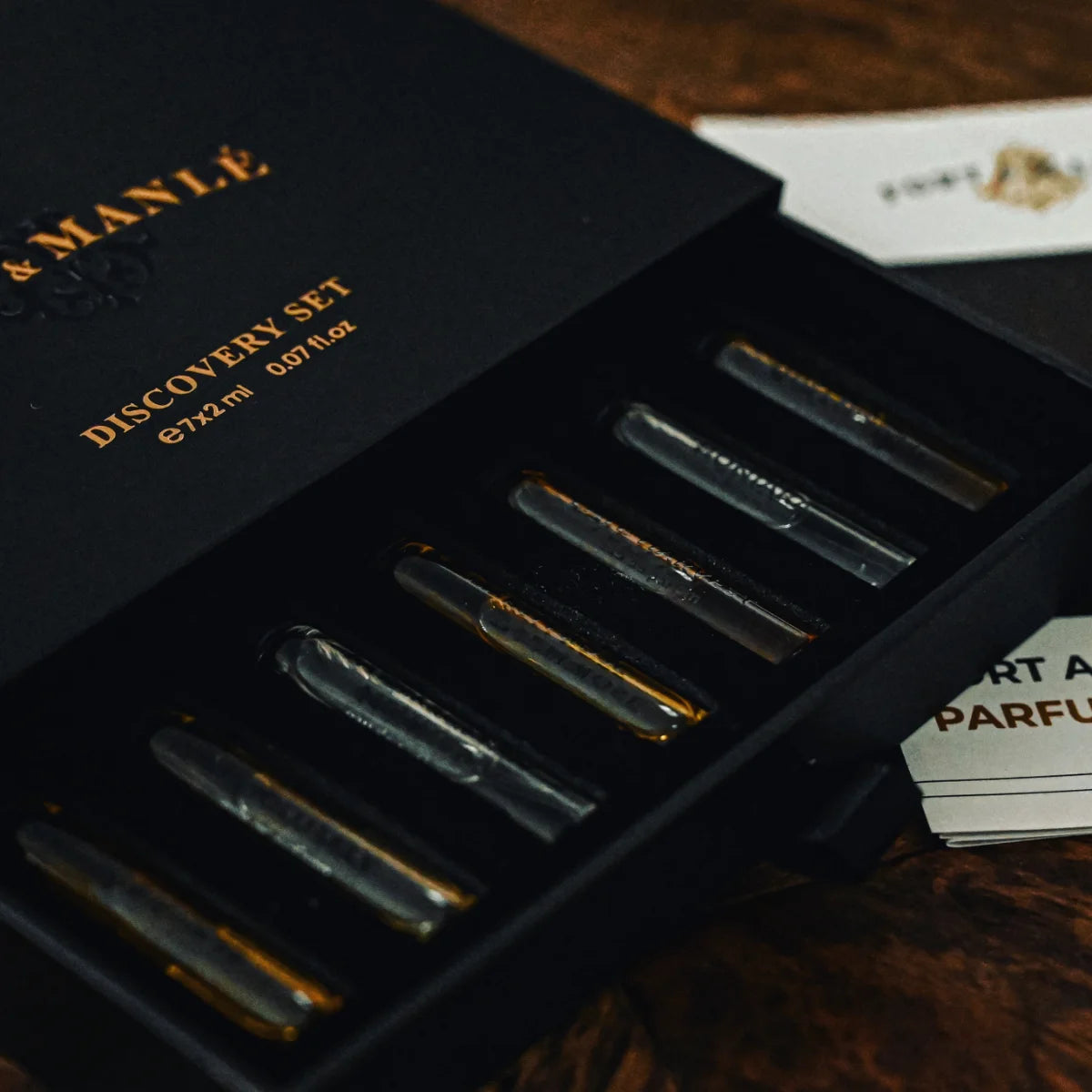 Fort & Manlé - Discovery Set mit acht 2ml Duftproben in edler schwarzer Verpackung auf dunklem Holzuntergrund