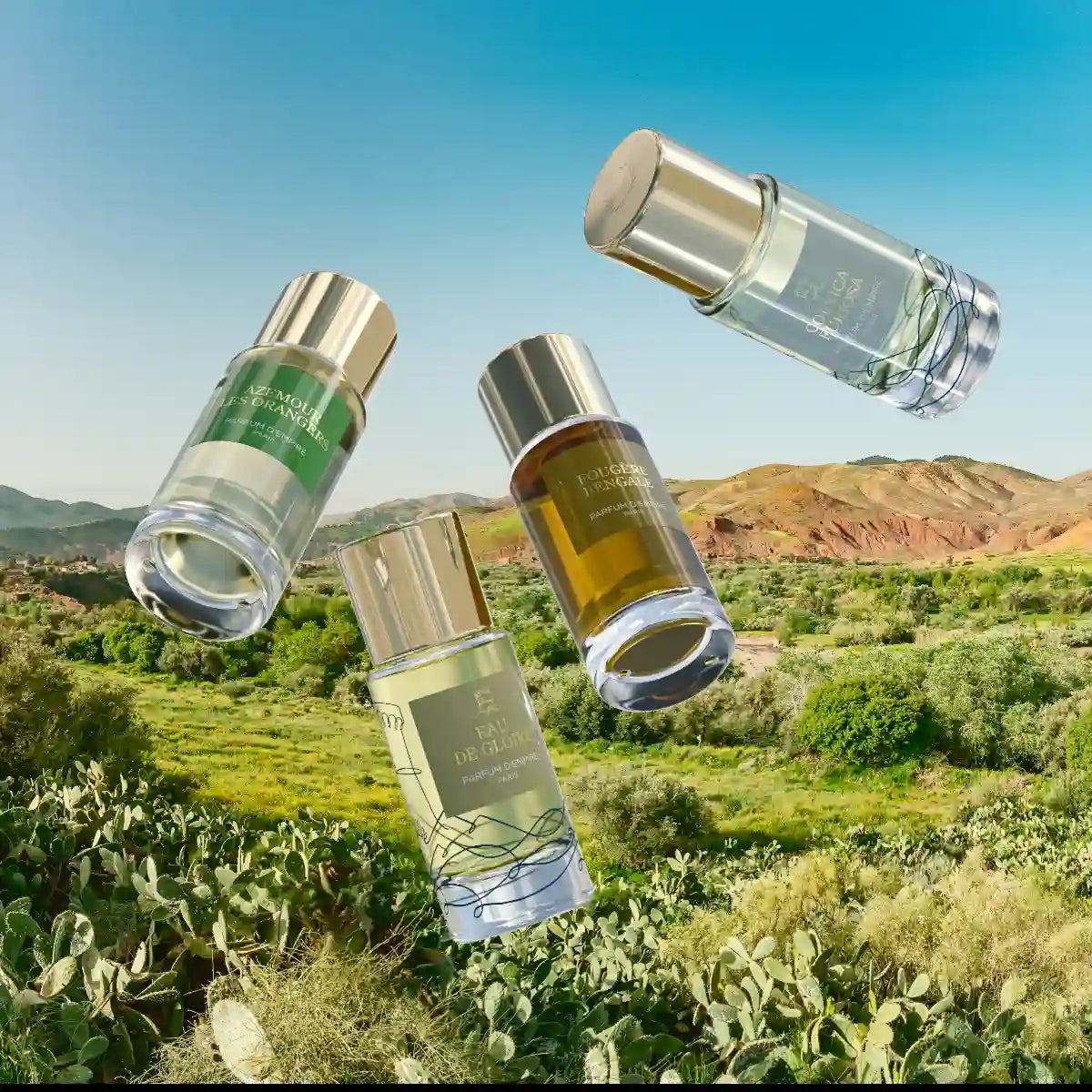 Parfum d'Empire - Fougère Bengale Flakon mit goldfarbenem Verschluss vor hellblauem Himmel und grüner Landschaft