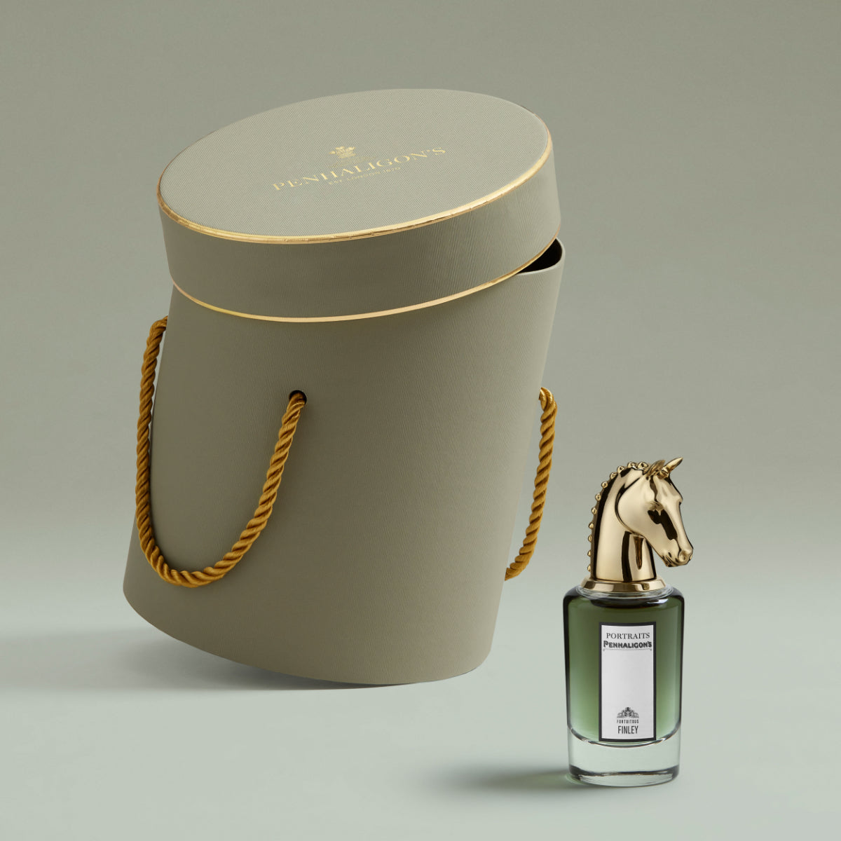 Penhaligon's - Portraits - Fortuitous Finley Flakon mit goldenem Pferdekopf vor eleganter grauer Geschenkbox mit goldener Kordel