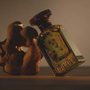 Anfas - Fosol Collection - Ghala zeigt kunstvollen Glasflakon mit bronzefarbenem Verschluss und warmem Lichtspiel