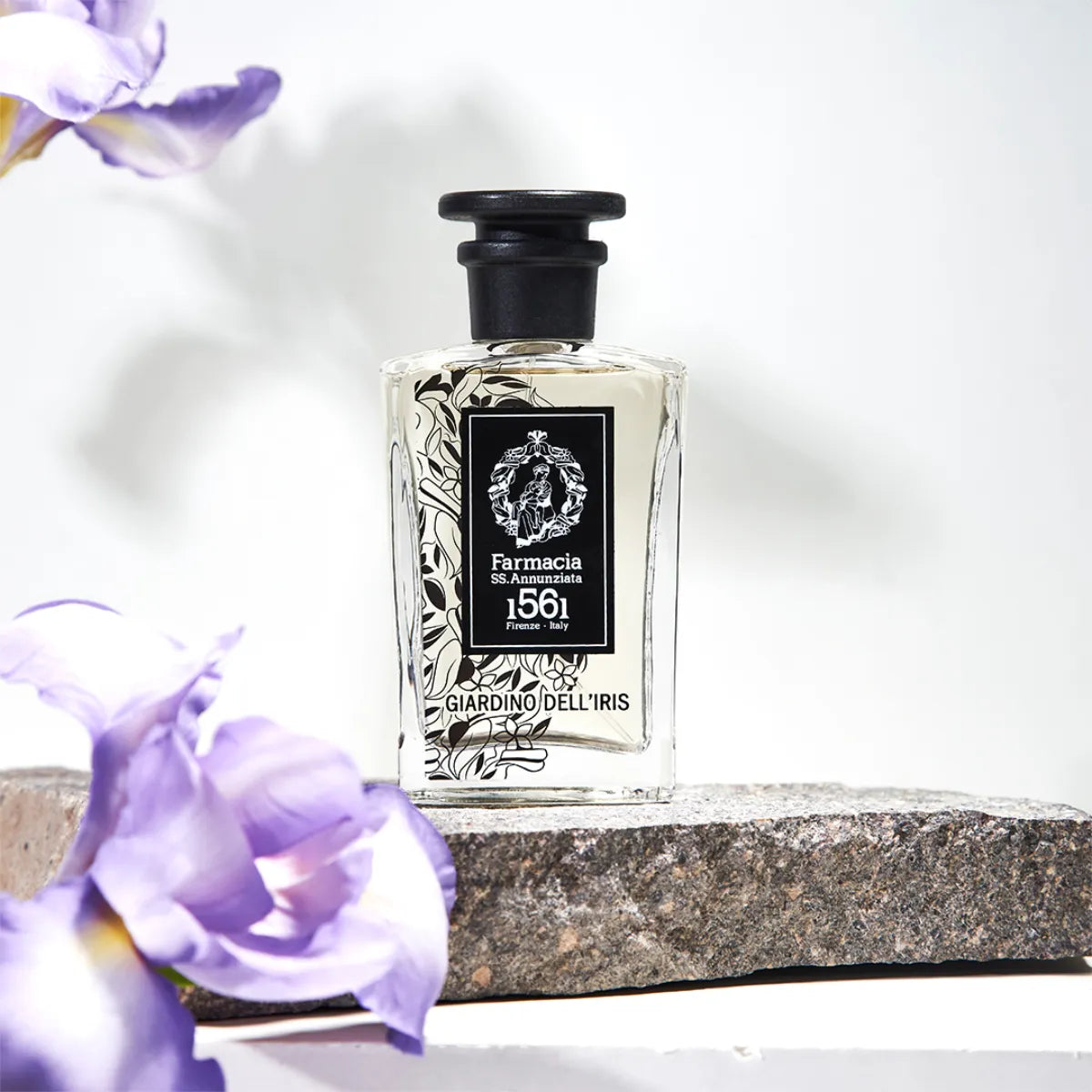 Farmacia SS. Annunziata - Giardino dell'Iris Duftflakon mit floralen Details auf Steinplatte vor hellem Hintergrund