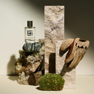 Estoras - Shadows of Giza Parfumflakon auf Naturstein mit Moos und handgestricktem Handschuh vor neutralem Hintergrund