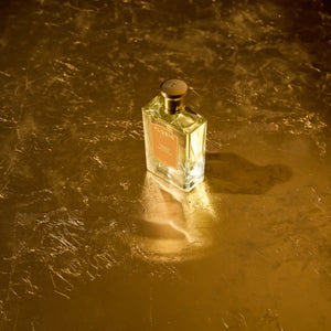 Floris - Golden Amber Parfumflakon auf goldfarben reflektierender Oberfläche mit warmem Lichtakzent