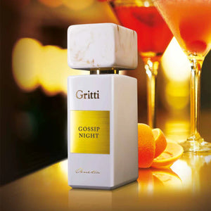 Gritti - White Collection - Gossip Night Parfumflakon in weiß mit goldfarbenem Etikett vor stilvollem Cocktail-Hintergrund
