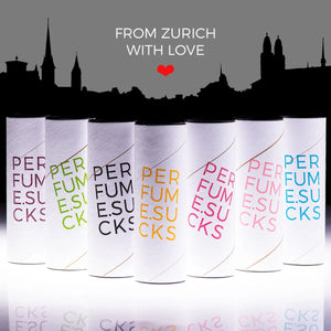 PERFUME.SUCKS - Purple 222C Flakon mit violetter Schrift in einer Reihe verschiedener bunter Parfumflakons auf weißem Hintergrund