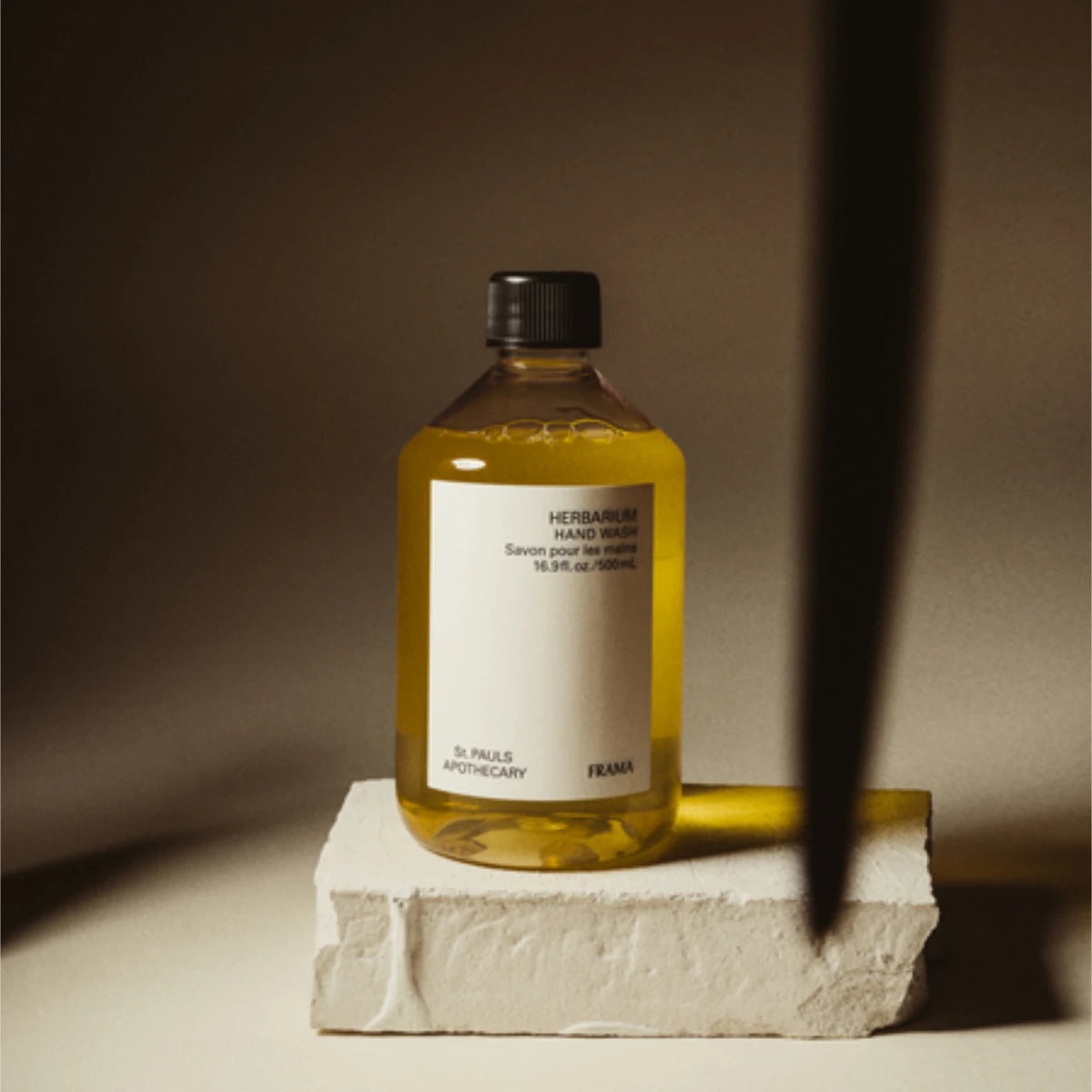 FRAMA - Herbarium - Hand Wash mildes Reinigungsgel in transparenter Flasche mit schwarzem Deckel vor warmem Hintergrund