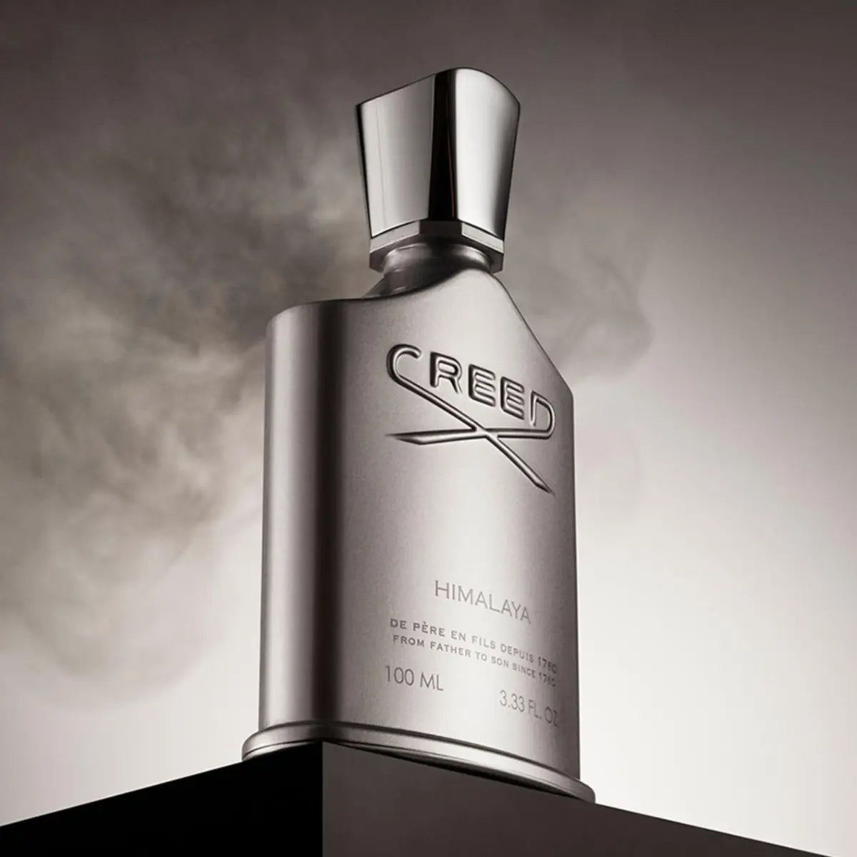 Creed - Himalaya Parfumflakon in markanter silberner Optik vor mystischem, nebligem Hintergrund auf schwarzem Podest