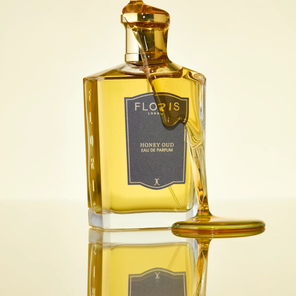 Floris - Honey Oud Parfümflakon mit honiggelber Flüssigkeit und goldfarbenem Verschluss in minimalistischem Stil