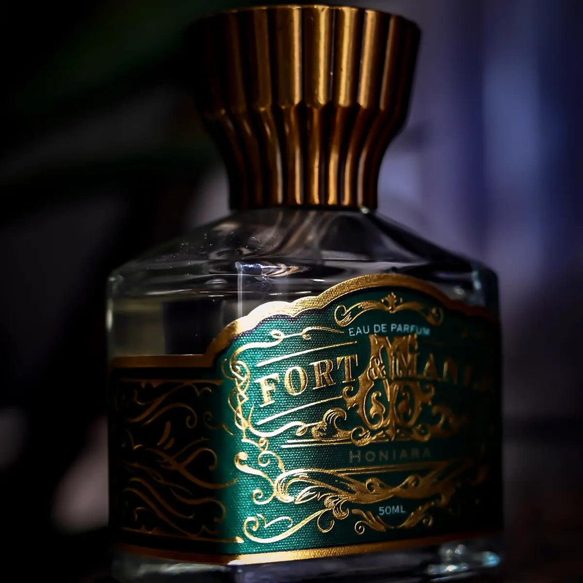 Fort & Manlé - Honiara Parfümflakon mit grünem, goldverziertem Etikett und elegantem bronzefarbenem Verschluss in ruhiger Atmosphäre